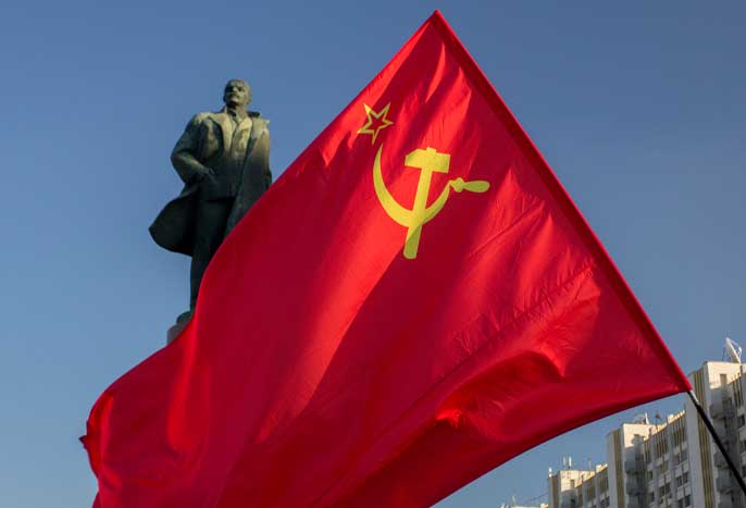 Le drapeau de l'Union soviétique (URSS) agitant au vent sur fond du monument à Lénine. Monument au leader communiste Lénine sous les rayons du soleil couchant.